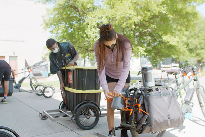 People loading bikes and trailers with food for delivery