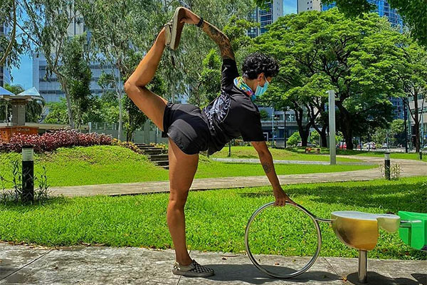 Aneka doing standing yoga pose in park on sunny day