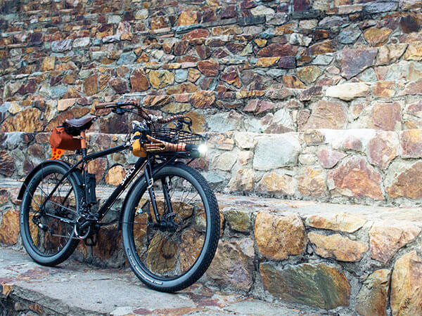 Custom Bridge Club with front rack, bag and light on, saddle bag, leaning agains rock amphitheater seating