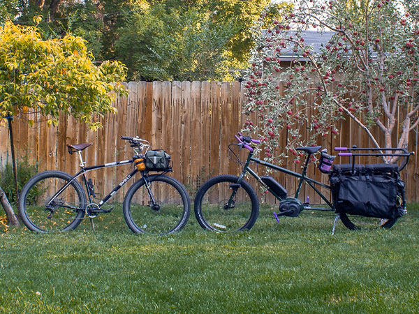 Abner's custom Bridge Club and Big Easy together in fenced backyard, front wheels nearly touching