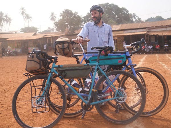 Person standing with three bikes, houses in background