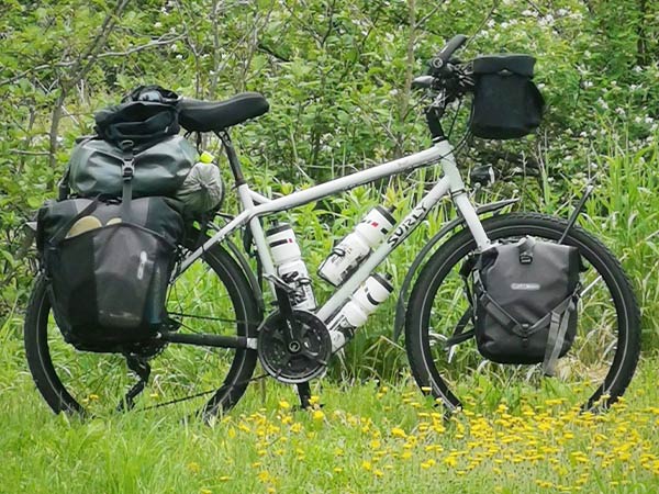 Assembled Troll build with racks, pannier bags, bags on top of rear rack, fenders, three bottles, and handlebar bag