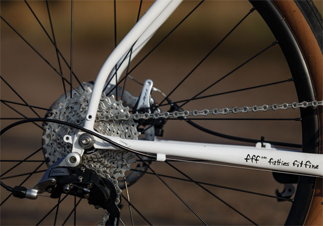 Zoomed in right side view of the rear axle plate, cassette and derailleur of a white Surly Midnight Special bike