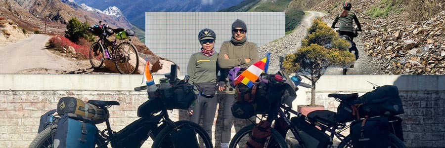 Dhruv and Ashim standing together with loaded Surly touring bikes in front of wall