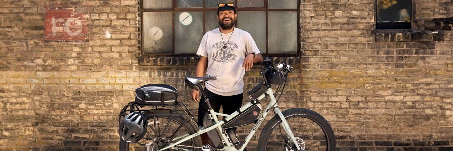 Alexis standing in front of building behind Surly Skid Loader bike smiling