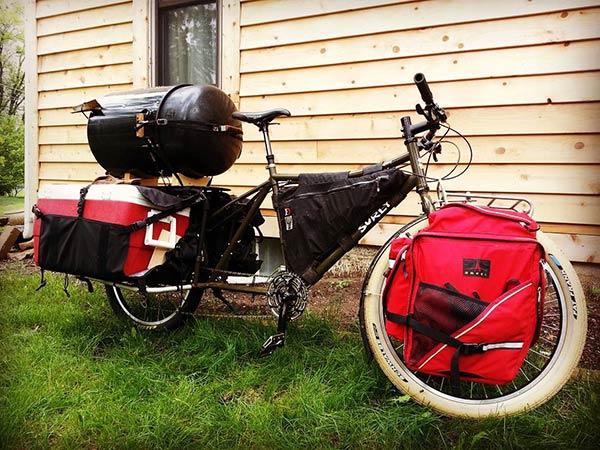 Surly Big Easy bike loaded with gear and smaller smoker on rear rack in front of a wood sided house