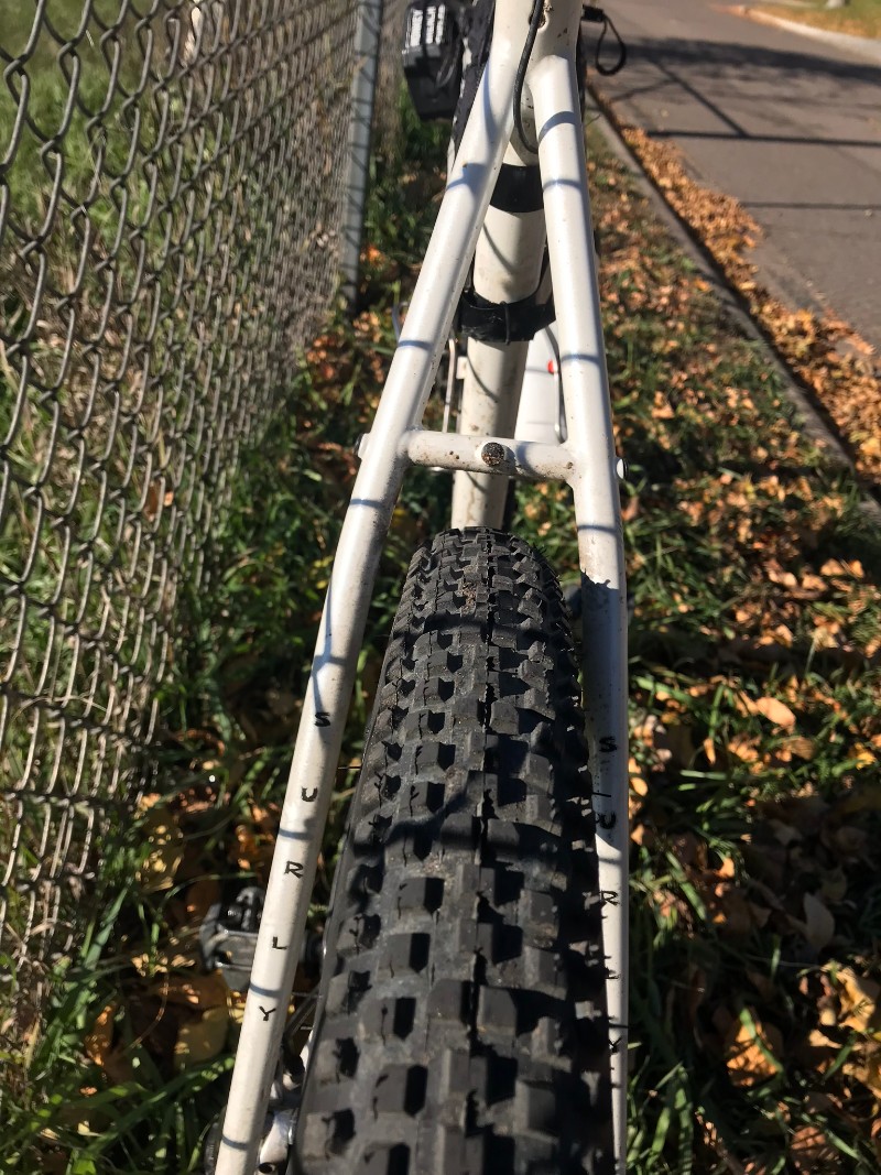 Zoom in of the seat stay and knobby rear tire of a white Surly Midnight Special