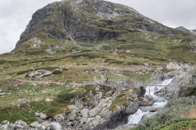 Person riding across a bridge over stream flowing down a mountain