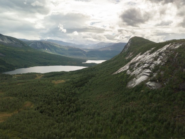 Overlook of tree covered mountains with two lakes white clouds and sun rays in the sky