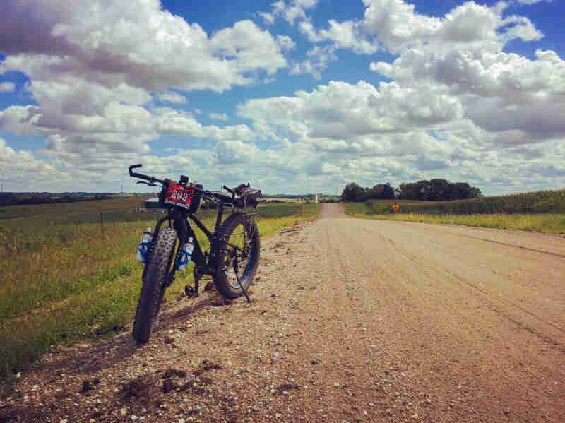 Front view of a Surly Ice Cream Truck fat bike, parked along the side of a gravel road with farm fields on the sides