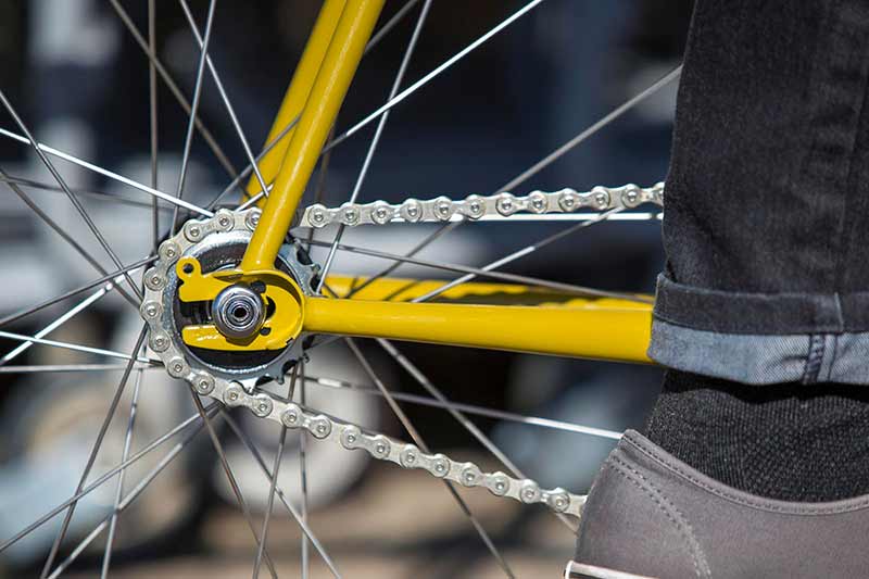 Close-up of drive-side rear wheel on yellow single speed bike