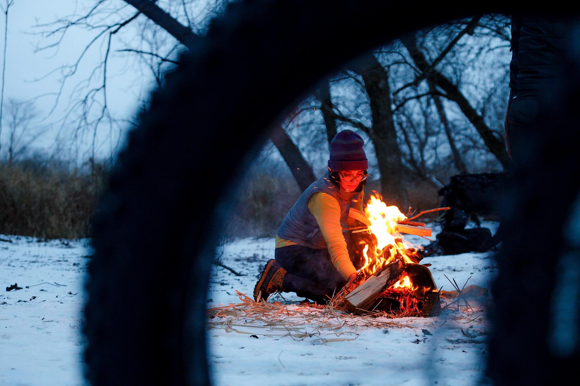 Person lighting a camp fire before sunset