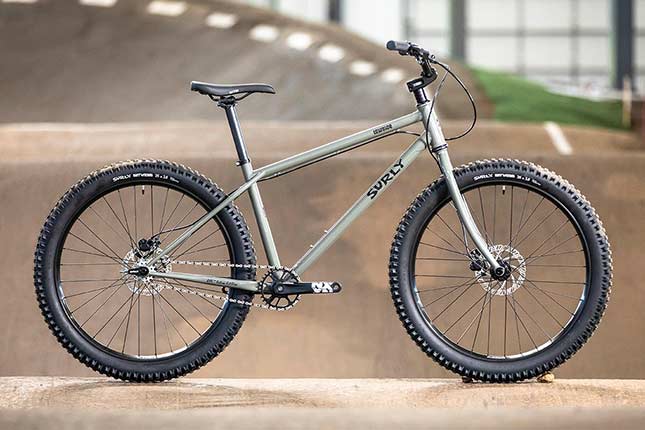 Gray Surly Lowside side view with 26-inch wheels, on indoor BMX track