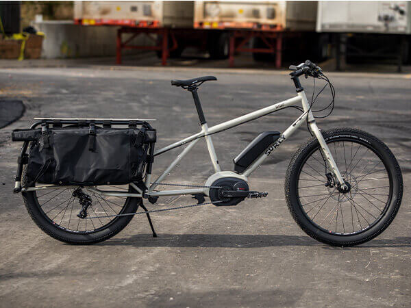 Surly Big Easy complete bike, side view, in parking lot with kickstand down, truck trailers and loading dock in background