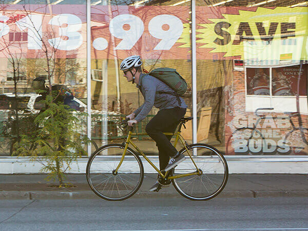 Cyclist wearing backpack riding Surly Steamroller on urban street