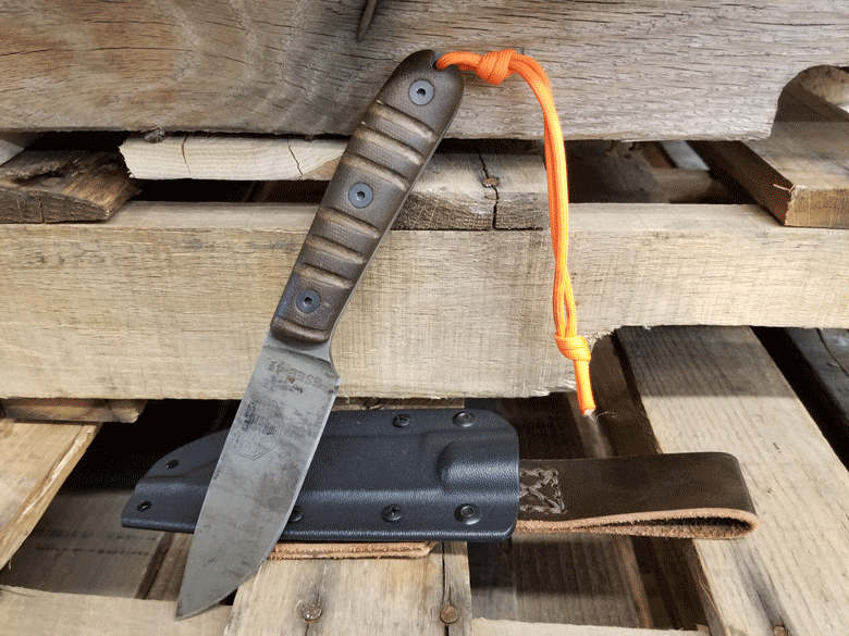 ESEE Knife with gray blade and wood handle laying on a blue and white woven blanket